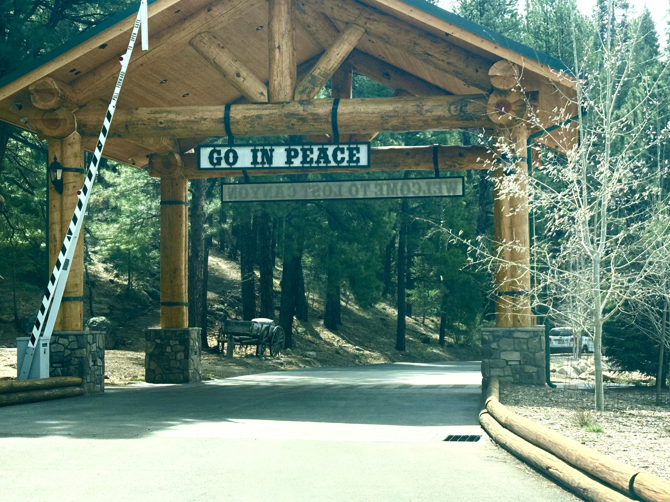Go In Peace Wooden archway displaying the words "Go In Peace" at Lost Canyon Young Life Camp in Williams, Arizona, surrounded by pine trees and mountain scenery.
