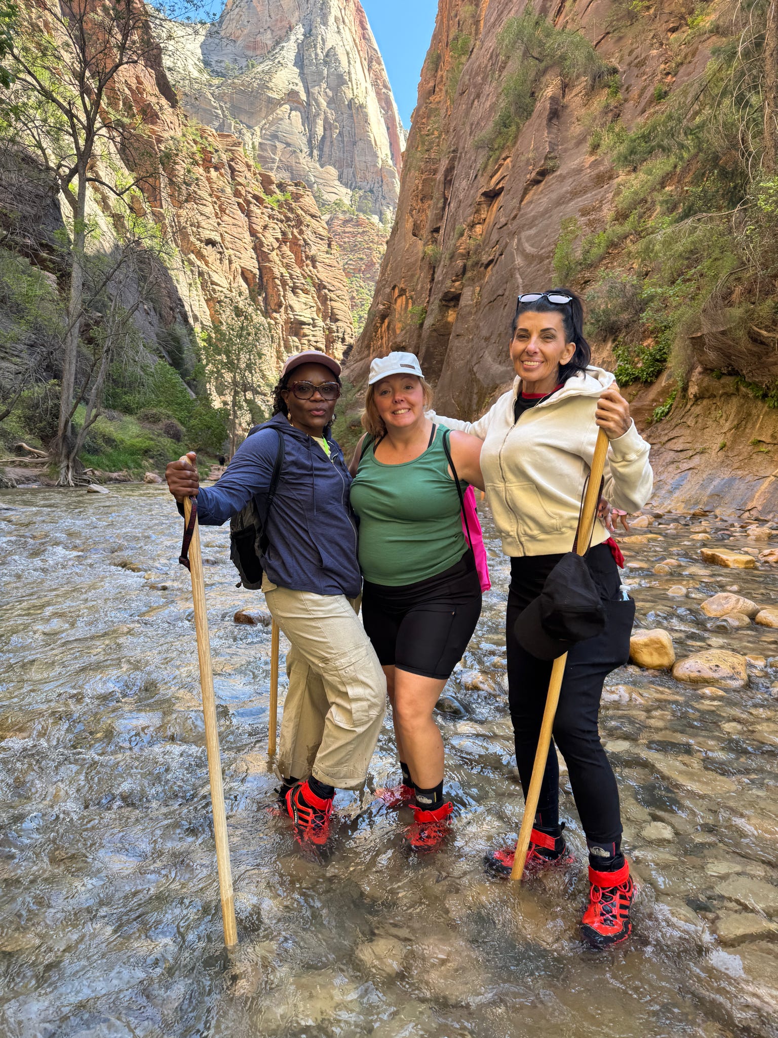 Three women standing in the Virgin River during The Narrows hike in Zion National Park.