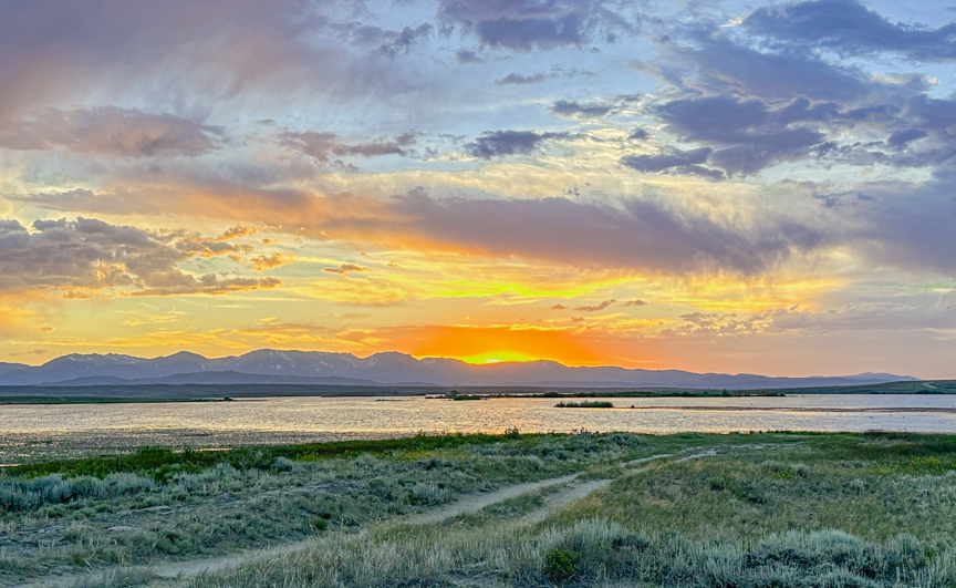 Golden sunset over a lake and distant mountains near a boondocking campsite in Walden, Colorado