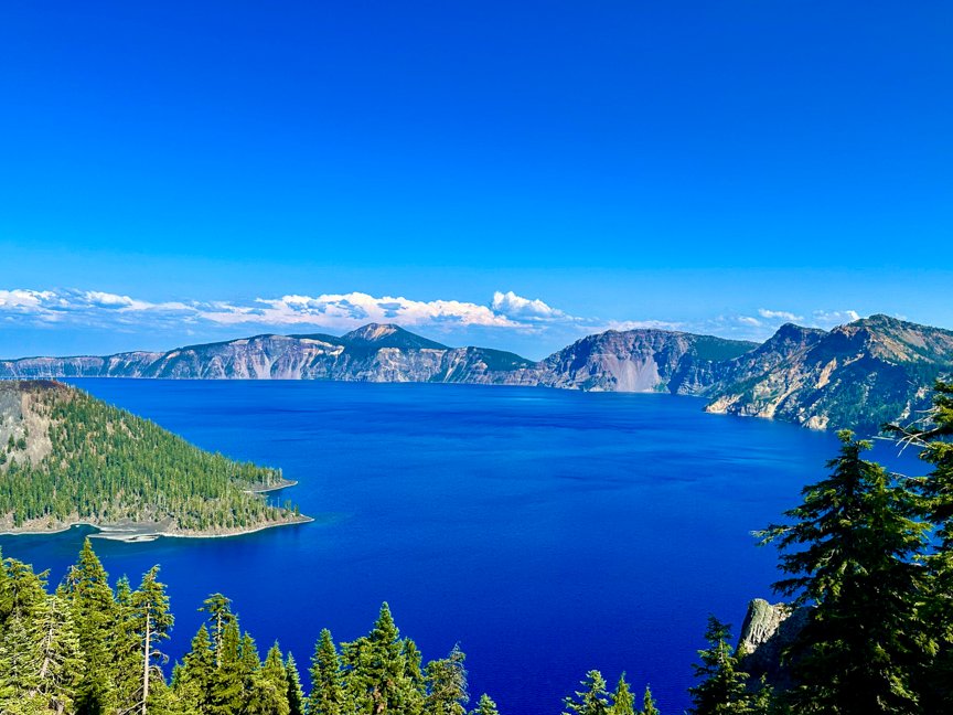 Wizard Island surrounded by the deep-blue water and steep volcanic cliffs of Crater Lake in Oregon