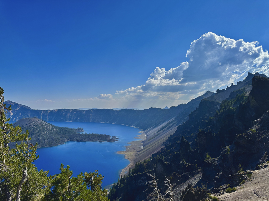 Panoramic view of deep-blue Crater Lake surrounded by volcanic cliffs and evergreen trees in Oregon