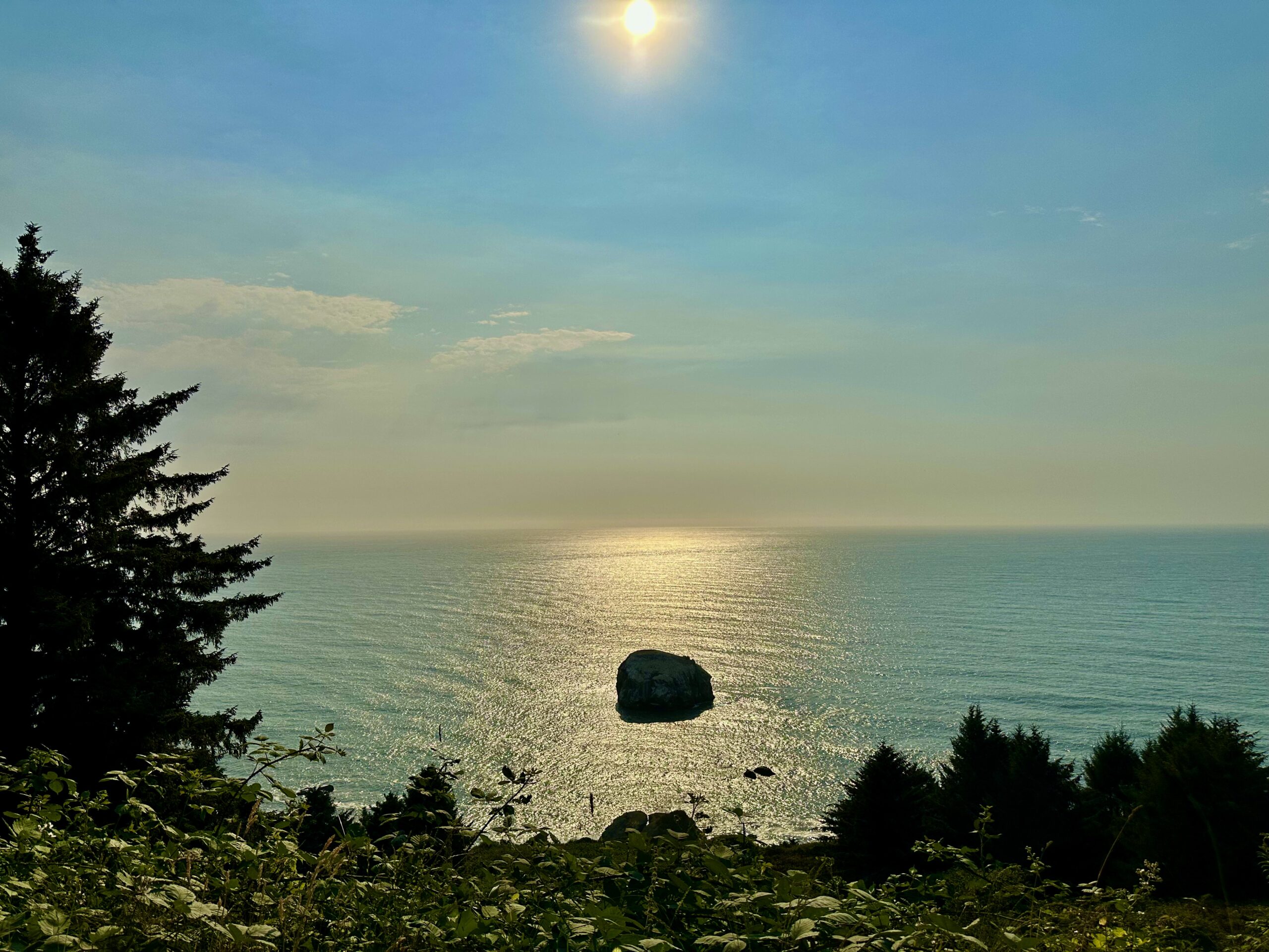 Sunlight reflecting across the Pacific Ocean around a solitary sea stack near Klamath, California