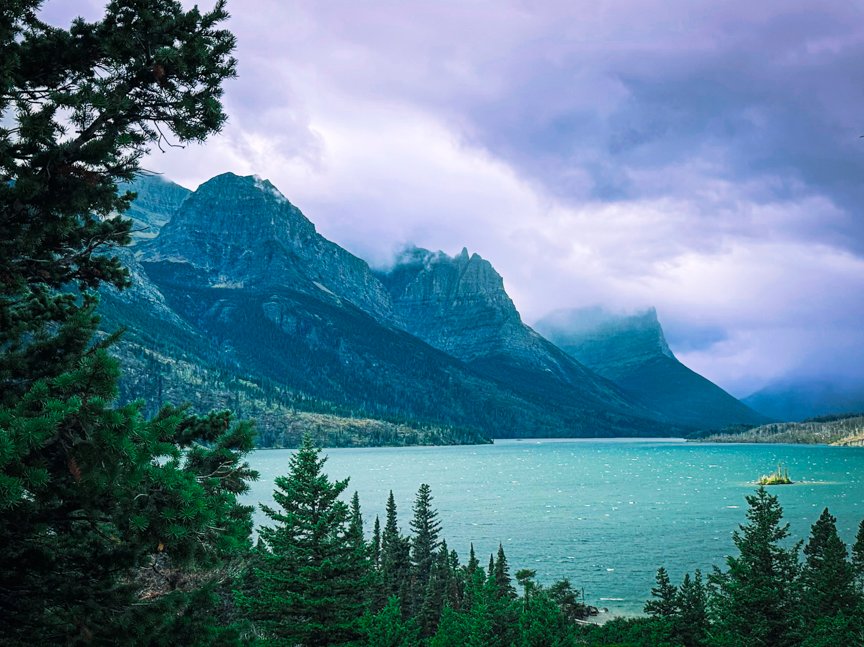 Wild Goose Island in turquoise Saint Mary Lake beneath cloud-covered mountains in Glacier National Park